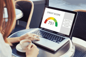 Person checking credit score on laptop with a gauge showing 751 score.