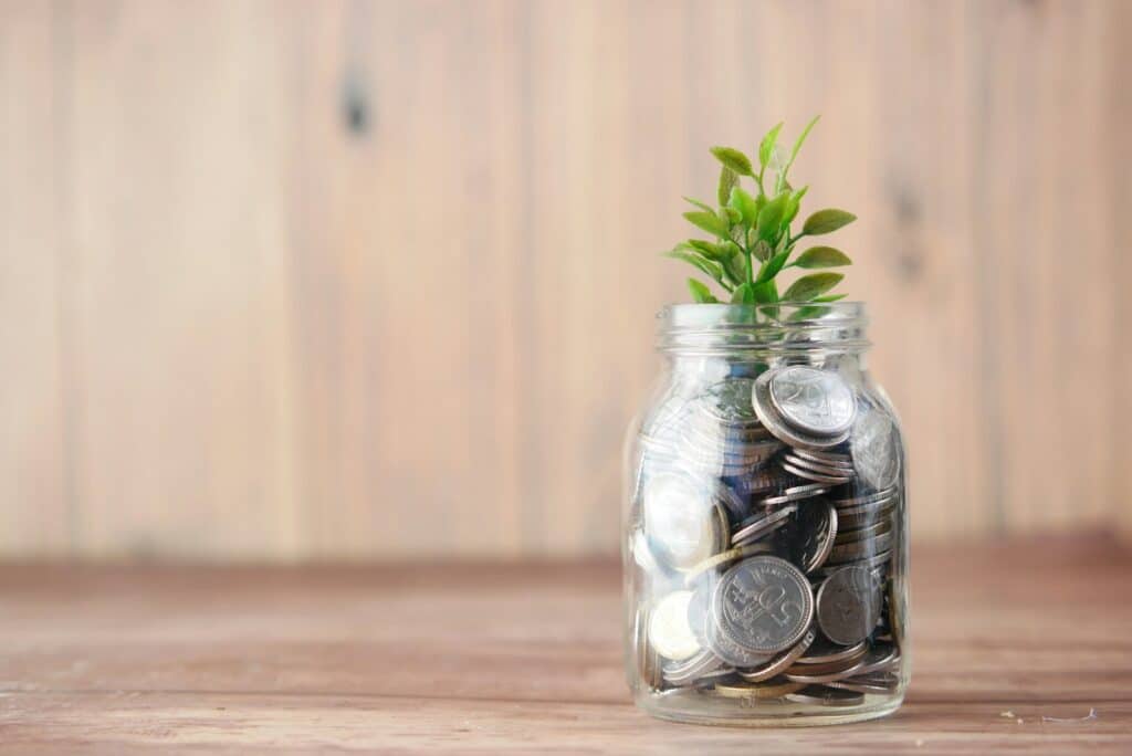 Glass jar of coins with a growing plant sprout, symbolizing rebuilding your credit and financial growth