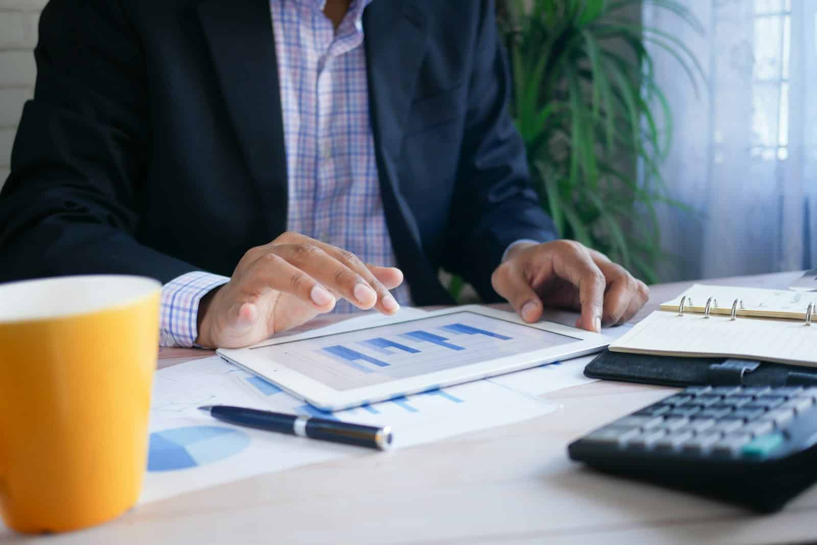 Asesor financiero revisando gráficos crediticios y financieros con un cliente en una tableta.